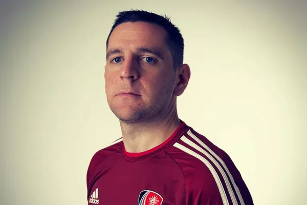 Imagem mostra Rob McPherson, que é um homem branco, vestido com uniforme de futebol e olhando para a câmera - Metrópoles