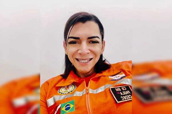 Mulher com cabelo curto preto e uniforme laranja dos bombeiros sorrindo