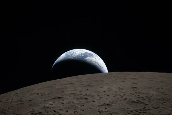 Imagem colorida mostra o lado oculto da Lua com a Terra no fundo - Metrópoles
