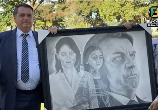 Bolsonaro segura quadro com desenho de sua família em frente ao palácio da Alvorada. O autor do quadro e apoiador do presidente segura do outro lado, só aparecendo suas mãos - Metrópoles