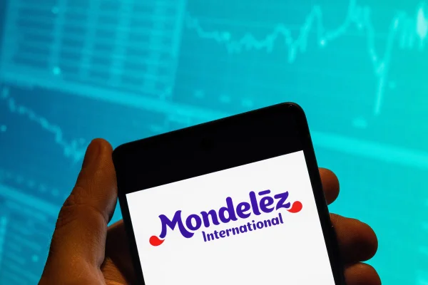 Imagem de celular com o logotipo da Mondelez International sendo exibido na tela, com um fundo azul - Metrópoles