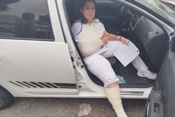 Imagem mostra mulher sentada em carro com a perna imobilizada - Metrópoles