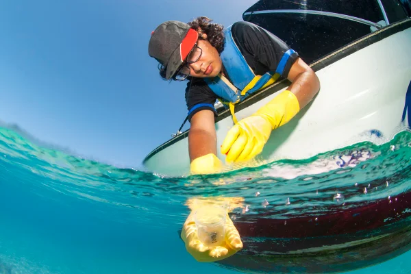 Imagem colorida de Bióloga analisando água do mar - Metrópoles- pfas