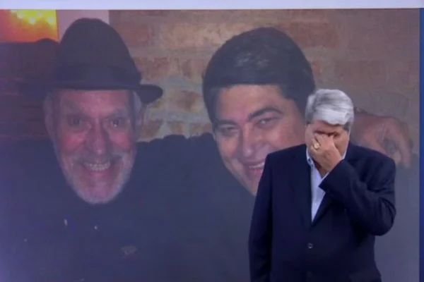 Imagem colorida de Datena com a mão no rosto e uma imagem dele com Silvio Luiz ao fundo. Metrópoles