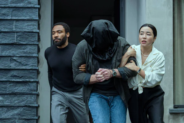foto de homem negro e mulher asiatica segurando pessoa com saco na cabeça - metrópoles