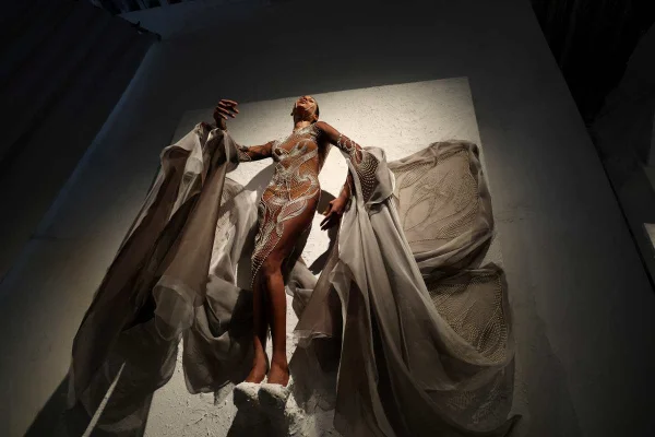 A imagem mostra uma mulher em uma parede durante uma exposição de Alta-Costura - Metrópoles