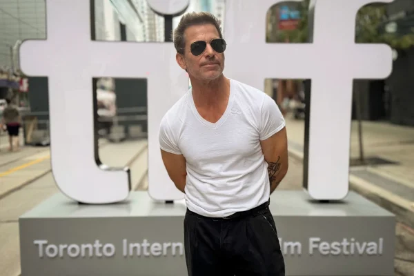 Imagem colorida de Zack Snyder no Festival de Toronto usando blusa branca e óculos de sol - Metrópoles