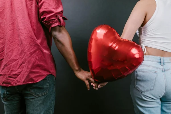 Casal segurando as mãos e um balão vermelho de coração