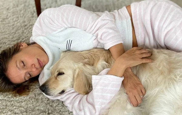 Luisa Mell deitada no chão abraçando cachorro