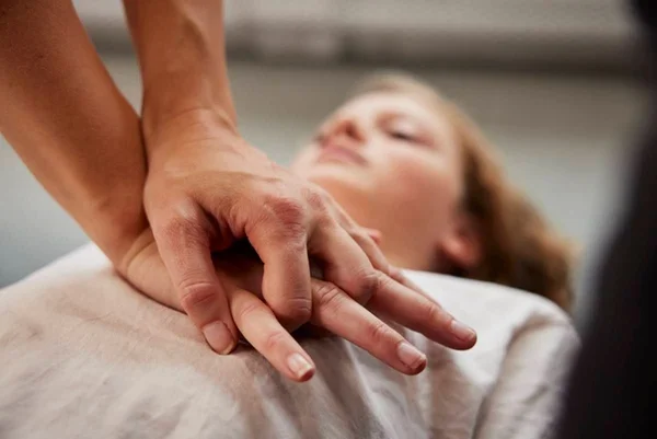 Imagem mostra pessoa fazendo primeiros socorros com as duas mãos no peito de mulher deitada - Metrópoles