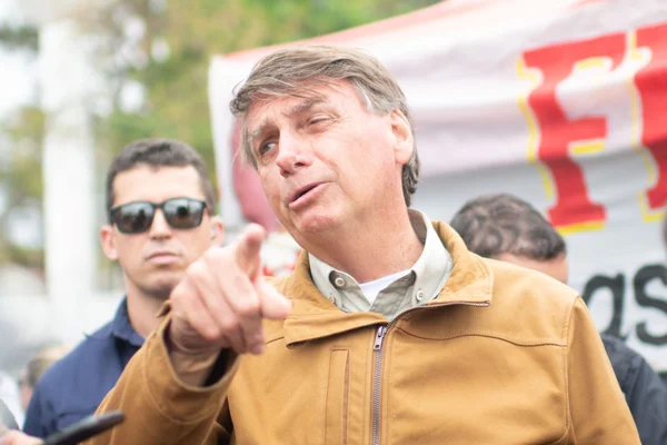 O presidente Jair Bolsonaro comendo churrasquinho em uma barraca no Guará, no DF