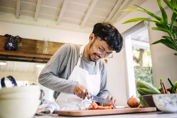 homem na cozinha cortando tomate