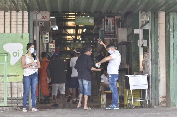 Consumidores recebem álcool gel em suas mãos, antes de entrarem na Feira de Ceilândia