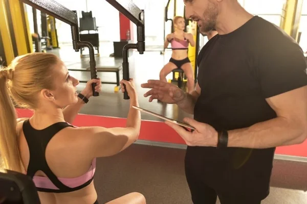 Mulher fazendo Musculação com professor na academia - Metrópoles