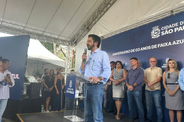 Imagem colorida mostra o prefeito de São Paulo, Ricardo Nunes, em evento falando em palco cercado por algumas pessoas - Metrópoles