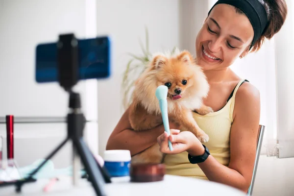 Mulher influenciadora gravando vídeo de maquiagem com seu cachorro