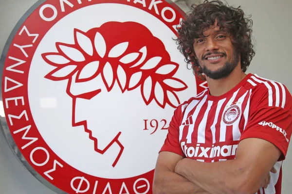 Imagem colorida de Gustavo Scarcpa em frente ao escudo do Olympiakos - Metrópoles