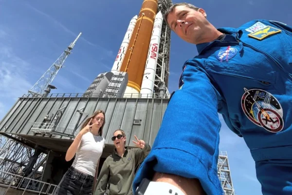 Imagem colorida mostra astronauta que irá à Lua com filhas em frente a foguete - Metrópoles