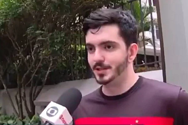 foto de homem jovem de pele branca com barba e cabelos escuros falando em microfone - metrópoles