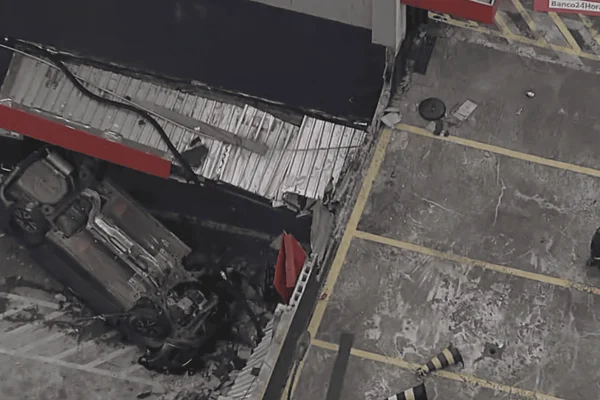 Imagem colorida de carro capotado após cair de estacionamento; mulher se feriu