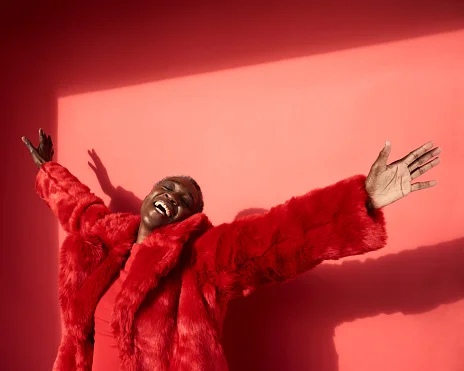 mulher sorrindo de braços abertos em fundo vermelho com amor