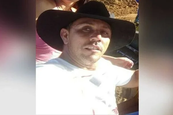 Homem branco com um chápeu preto e blusa branca