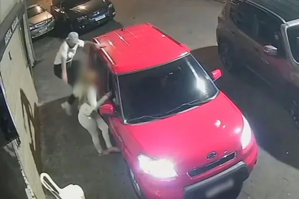 Imagem colorida mostra a vítima do lado de fora do carro enquanto é atingida pela voadora do ex-namorado