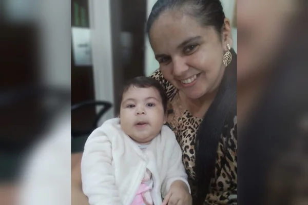 Foto colorida de mulher de cabelos longos com uma bebê de pele branca e rechonchuda. Ela teve AME e usou o remédio milionário Zolgensma