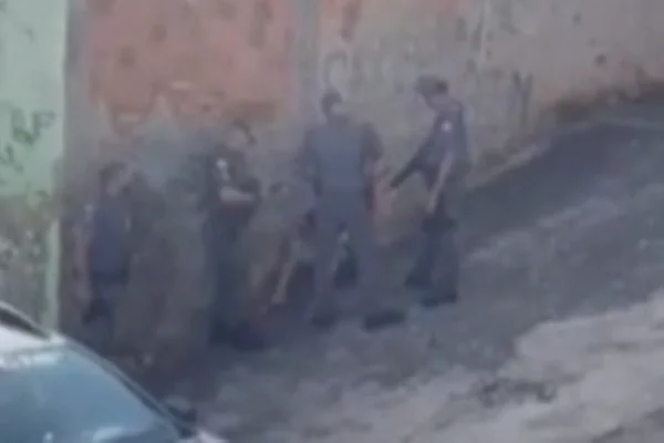 Imagem colorida de quatro policias cercando um homem e sentado na calçada - Metrópoles