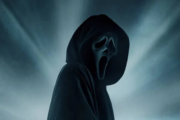 Antagonista do filme "Pânico 6" em divulgação. Ele usa capa preta, máscara branca e olha de perfil para a câmera - Metrópoles