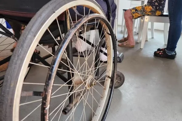 Imagem colorida cadeira de rodas com perna de idosa na frente em clínica - Metrópoles