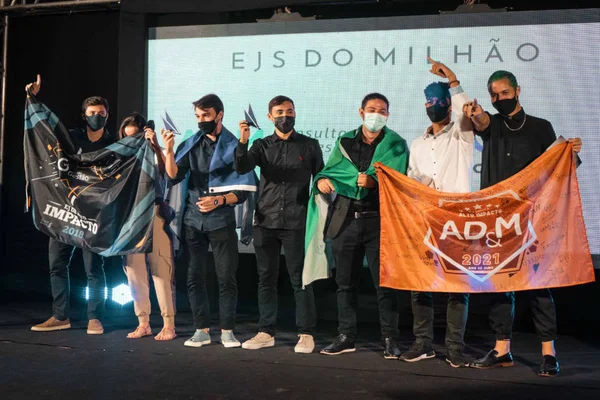 pessoas seguram bandeiras de empresa e troféus