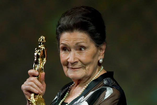 Foto colorida de Ana Ofelia Murguía segurando estatúa dourada - Metrópoles