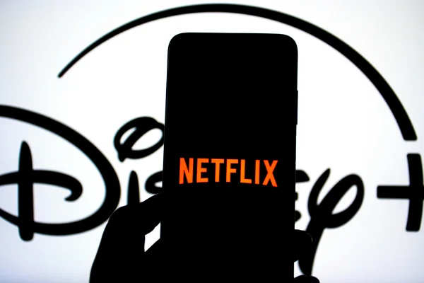 Nesta foto ilustrativa, o logotipo da Netflix aparece exibido em um smartphone, com o logotipo do Disney+ ao fundo - Metrópoles