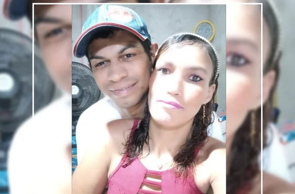 Em foto colorida casal do qual homem de boné abraça mulher de camiseta rosa por trás - Metrópoles