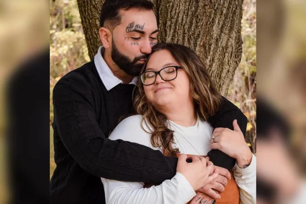Foto colorida de homem abraçando mulher, encontados em uma árvore - Metrópoles.