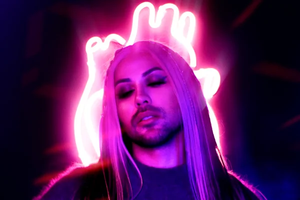 Foto colorida de Samira Close. A drag queen está iluminada por neon e com peruca loira - Metrópoles