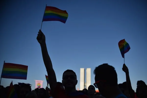 Pessoas segurando bandeira LGBT- Metrópoles