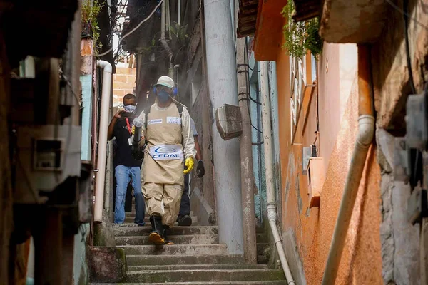 Homem usando roupas especiais faz a limpeza de uma favela do rio de janeiro