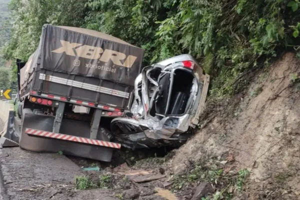 Imagem colorida de carro prensado por caminhão - Metrópoles