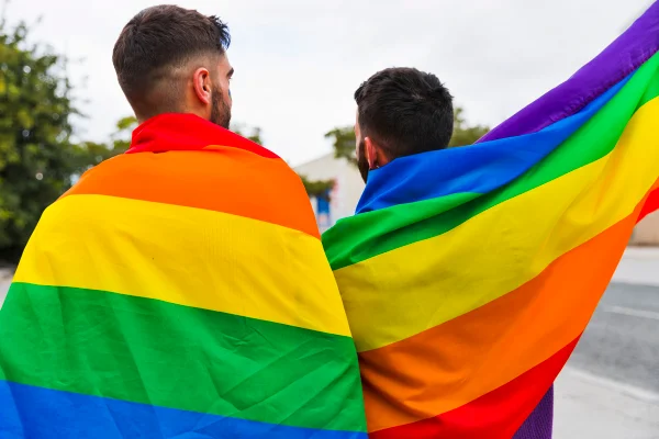 Foto colorida de dois homens com bandeira LGBT