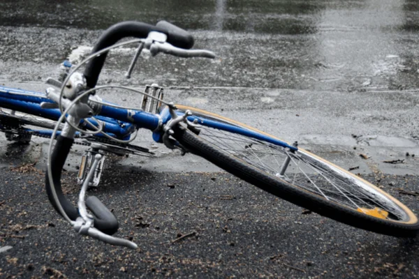 Imagem colorida de uma bicicleta quebrada jogada em uma rodovia - Metrópoles
