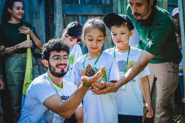 Fotografia colorida mostrando homem segurando tartaruga perto de crianças no zoológico-Metrópoles