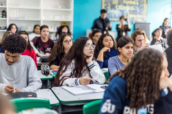 Imagem colorida mostra alunos do ensino médio em sala de aula.