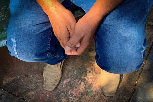 Mãos de homem sobre calça jeans azul