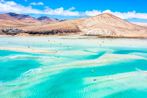 Praia com água azul turquesa e montes ao fundo