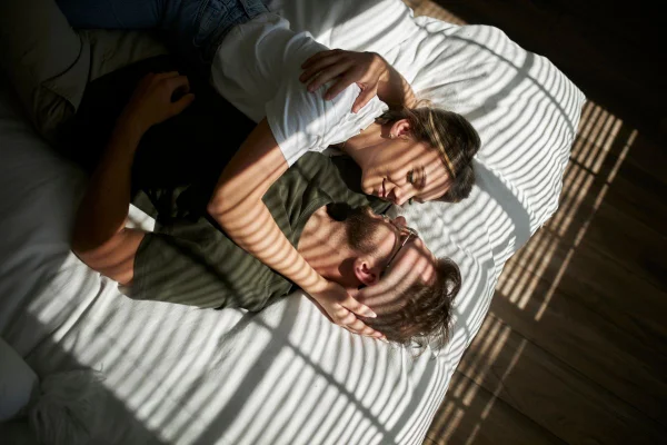imagem colorida de um homem e uma mulher deitados em uma cama