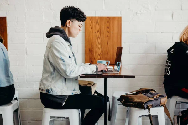 Fotografia colorida mostrando mulher mexendo em computador em café-Metrópoles