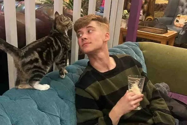 Foto colorida de adolescente com gato ao lado - Metrópoles