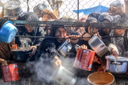 Palestinos recebem refeições  distribuídas por organizações humanitárias na área de al-Mawasi, em Khan Yunis, Gaza